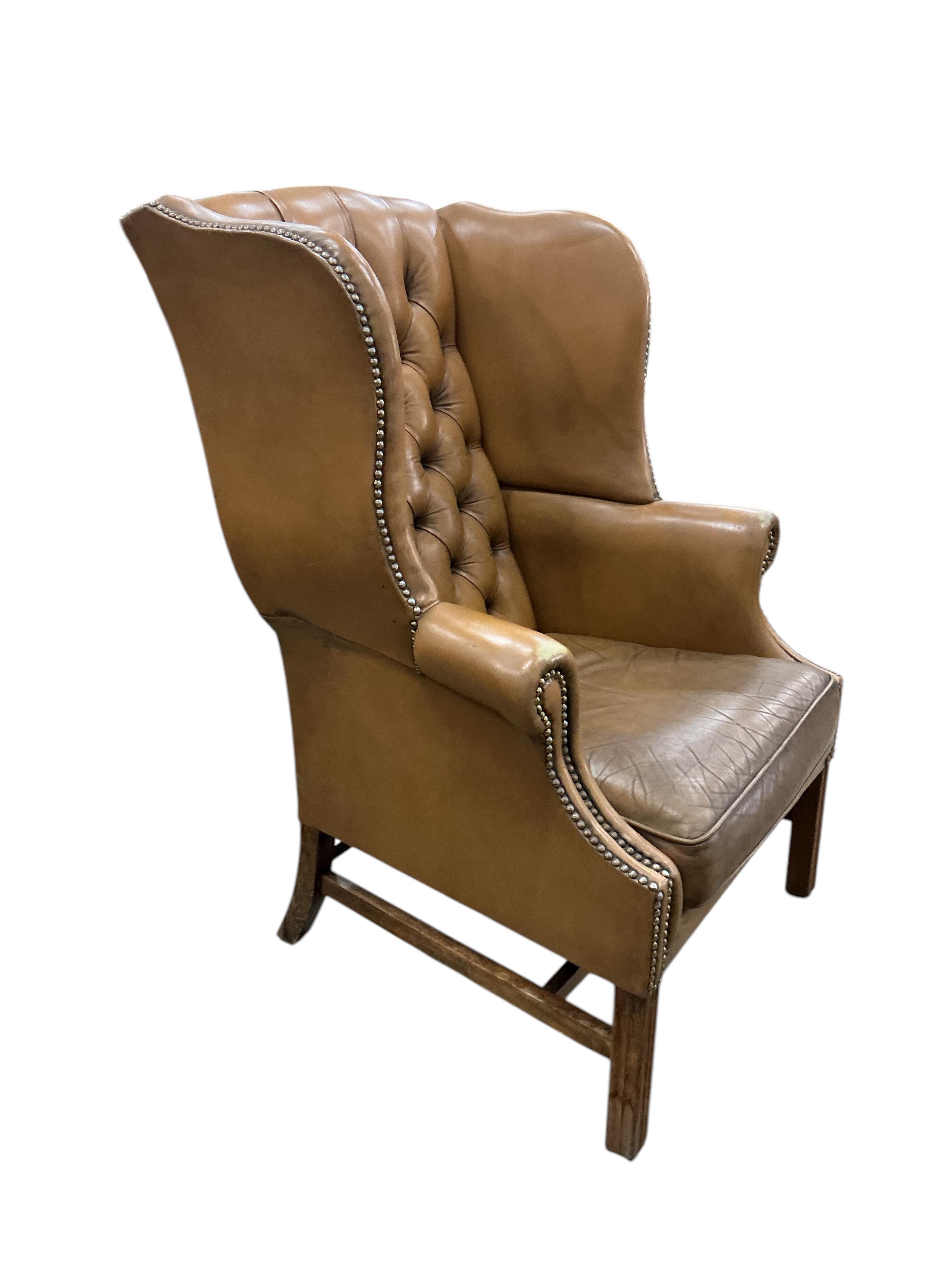 A George III style buttoned tan leather wing armchair, width 74cm, depth 74cm, depth 64cm, height 108cm